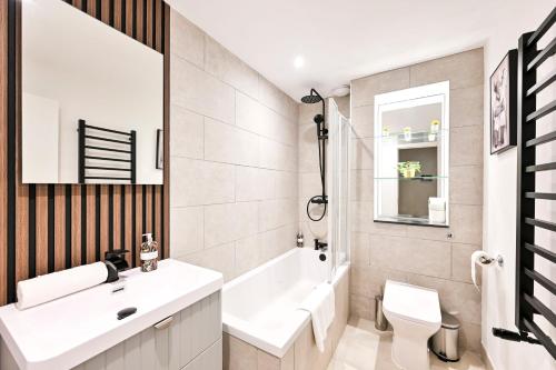 a bathroom with a sink and a tub and a toilet at Stylish Marylebone Apartments in London