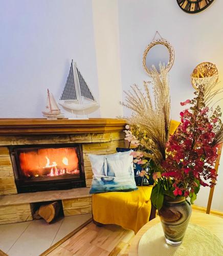 a living room with a fireplace and a vase with flowers at Polańczyk Dom, Apartamenty - Leśny Domek Polańczyk in Polańczyk