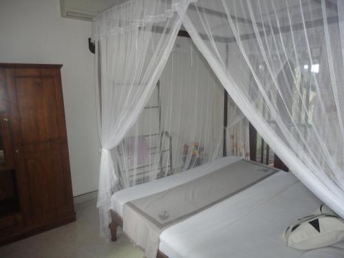 a bedroom with a white bed with a canopy at Sapara River Guest in Bentota