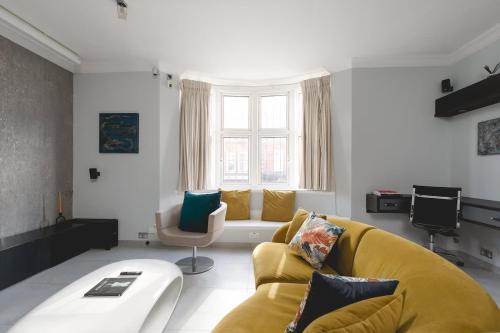 a living room with a yellow couch and a window at Regent's Park 1 bed with terrace in London