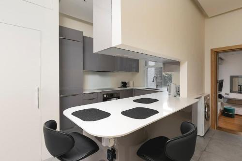a kitchen with a white counter and black chairs at Regent's Park 1 bed with terrace in London
