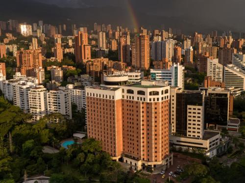 a city skyline with a rainbow in the sky at Hotel Dann Carlton Medellín in Medellín