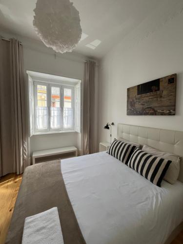 a bedroom with a large white bed with striped pillows at Casa 27 - Sete Rios in Lisbon