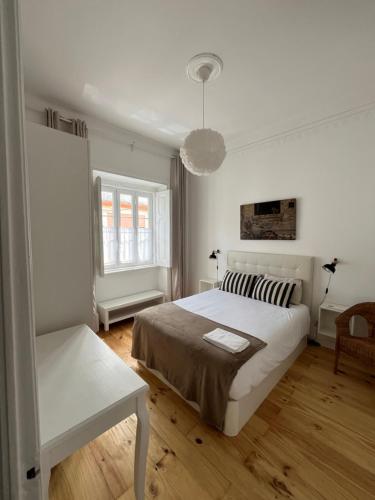 a white bedroom with a large bed and a chair at Casa 27 - Sete Rios in Lisbon