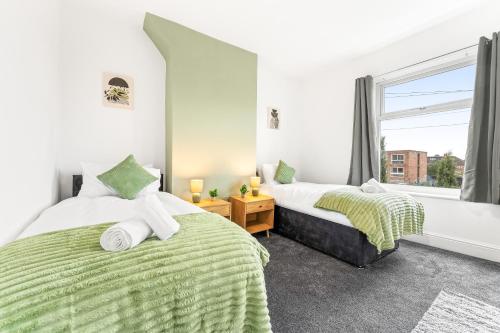 two beds in a room with a window at Comfortable 4 Bed Home - Free Parking & Brand New Bathroom in Denton