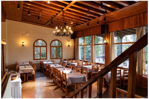 a dining room with tables and chairs and windows at Milionis Forest Hotel in Grevena