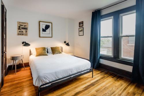 a bedroom with a bed and two windows at Luxe Mid-Century Styled Historic Townhouse #1 in Detroit