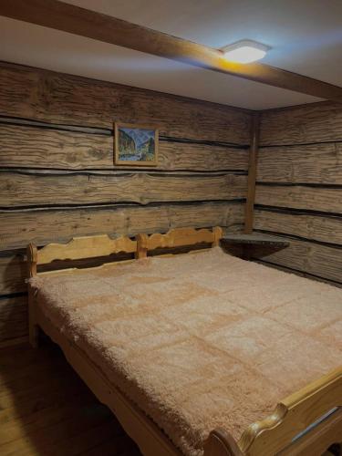 a bed in a room with a wooden wall at Pryhirska Sadyba in Torunʼ
