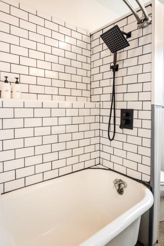 a white bath tub in a bathroom with white tiles at Luxe Mid-Century Styled Townhouse #3631 in Detroit
