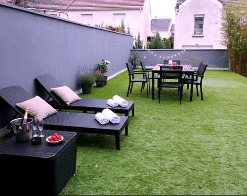 a patio with a table and chairs on the grass at Luxury & Love - Professional Jaccuzzi and Spa in Chelles