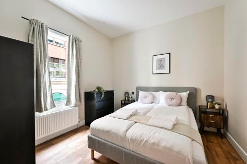 a bedroom with a bed with white sheets and pink pillows at Stylish Marylebone Apartments in London