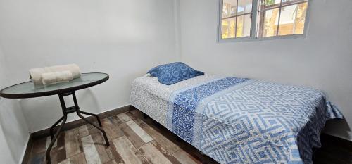 a bedroom with a bed and a table and a window at Habitación en villa Costa del sol in Los Blancos