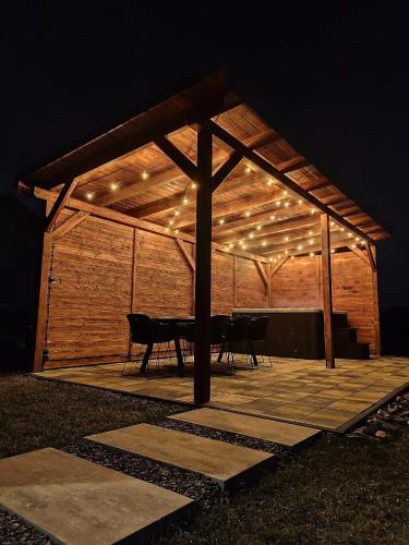 a pavilion with a table and lights on it at night at Górska Stodoła - Domek z Prywatnym Jacuzzi in Lipowa