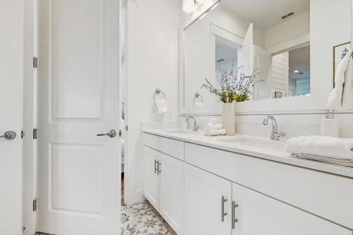 a white bathroom with a sink and a mirror at The Fairway Farmhouse in Port Aransas