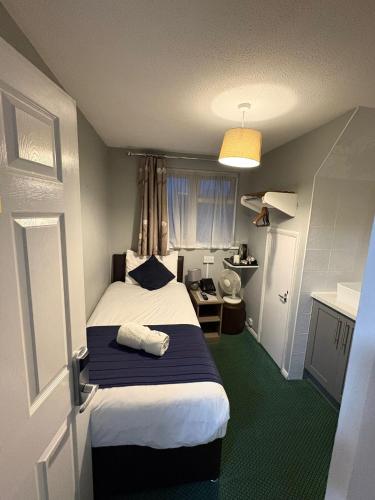 a bedroom with a bed with a blue and white blanket at Corner House Hotel Gatwick with bookable Holiday parking in Horley