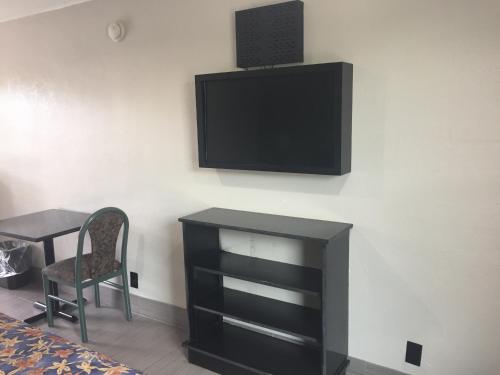 a tv on a wall with a desk and a chair at Fort Myers Inn in Fort Myers