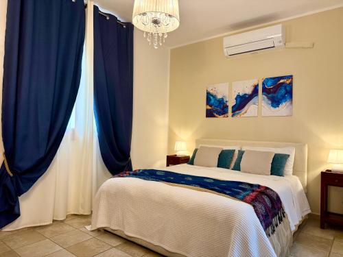a bedroom with a bed with blue curtains and a chandelier at Blue Dolphin Guest House in Alghero