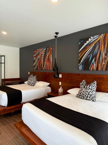 two beds in a room with paintings on the wall at Hotel Kumiai Inn in Tecate