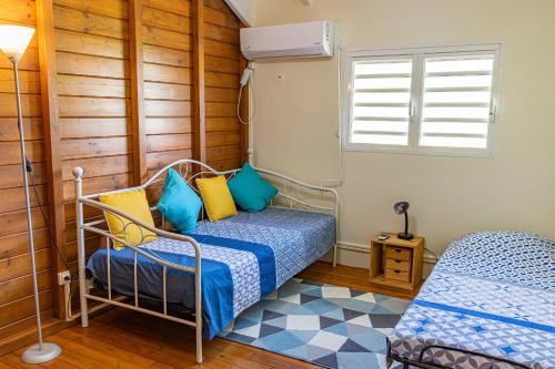 a bedroom with a bed with blue and yellow pillows at Kaz KOKOYE in Baie-Mahault