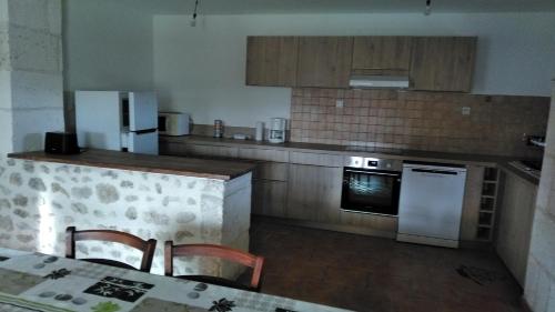 a kitchen with a counter and a table with chairs at Le Gîte de Mayac,16 rue du four à pain, 24600 VILLETOUREIX FRANCE in Villetoureix