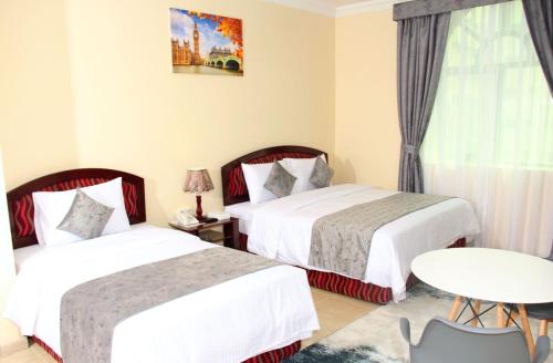a hotel room with two beds and a table at BARAKAH HOTEl in Sharjah