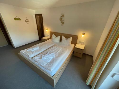 a bedroom with a bed with white sheets and pillows at Gästehaus Hauser in Bach