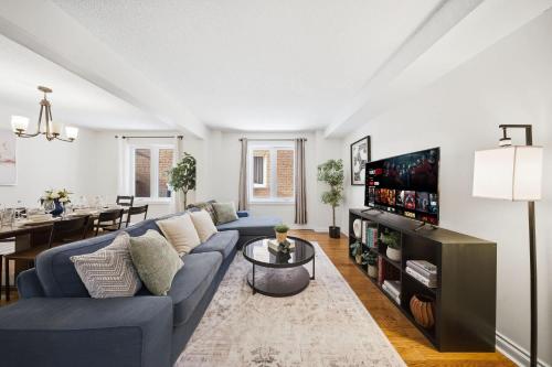 a living room with a blue couch and a tv at Huge 4 Bedroom House Near Square One - Sleeps 8 in Mississauga