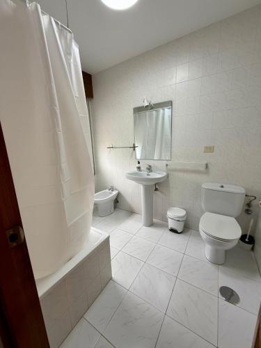 a white bathroom with a toilet and a sink at Pensión O Regato in Redondela
