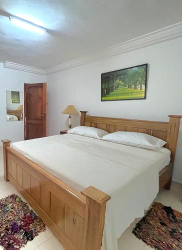 a bedroom with a large bed with white sheets at Aburi Emerald Garden Retreat in Aburi