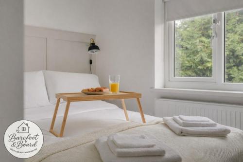 a bed with a table with towels and a glass of orange juice at Contractor friendly 3BDR Home | Parking for Vans in Salford