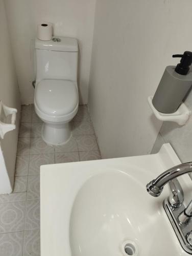 a white bathroom with a toilet and a sink at Cómodas Casas en el centro de Coatepec Veracruz in Coatepec