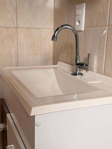 a white sink with a faucet in a kitchen at Chalés recanto dos oliveira in Camanducaia
