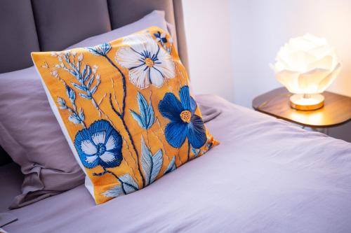 an orange pillow with blue flowers on a bed at City Square, center in Subotica