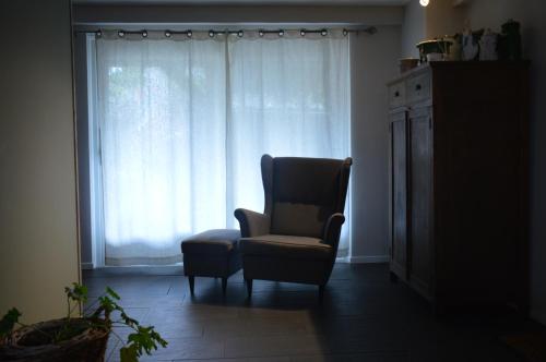 a living room with a chair and a window at Hoeve de Mertel in Biezenmortel