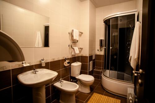 a bathroom with two toilets and a sink and a shower at Hotel Tsentralnaya in Gomel