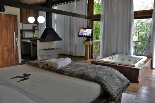 a bedroom with a large bed and a bath tub at Residencial Warabi in Visconde De Maua