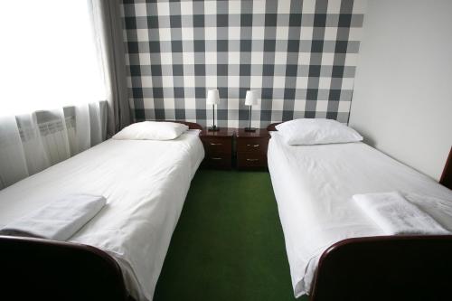 two beds in a small room with green carpet at Labirynt in Łomża
