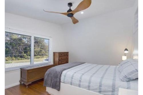 a bedroom with a ceiling fan and a bed at Dreamtime - 5 Ward St Hat Head NSW 2440 in Hat Head
