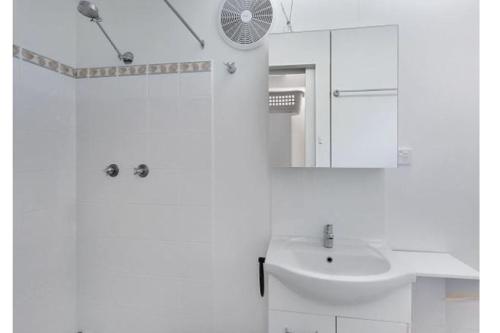 a white bathroom with a sink and a mirror at Dreamtime - 5 Ward St Hat Head NSW 2440 in Hat Head