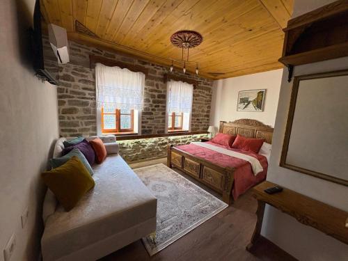 a bedroom with a bed and a couch in a room at Stone Pazar Guest House in Gjirokastër
