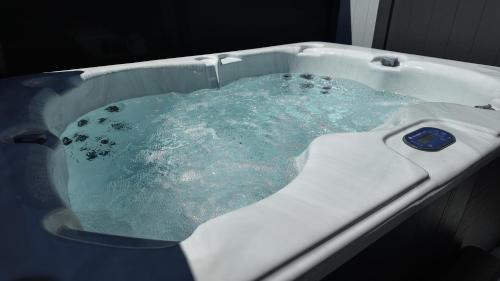 a bath tub filled with blue water at Taupo Premium Retreat - Private Spa & Ensuite in Taupo