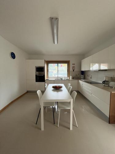 a white kitchen with a white table and chairs at Alojamento Local Pando in Vila do Conde