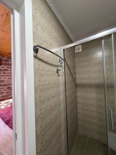 a shower with a glass door in a room at Stone Pazar Guest House in Gjirokastër