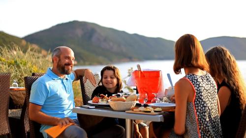 a group of people sitting at a table with food at Village de vacances Paese di Lava, Grand Ajaccio in Alata