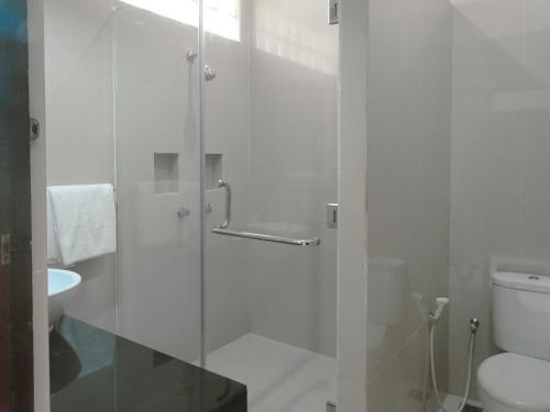 a bathroom with a glass shower with a toilet at Fat Yogi Cottages in Kuta