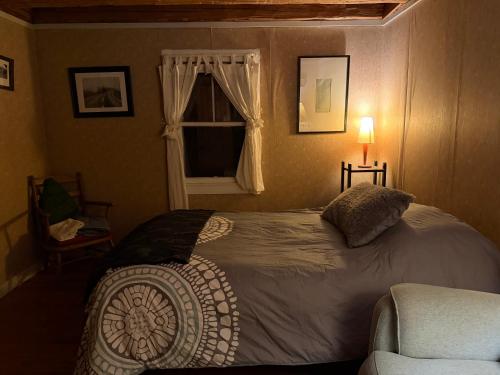 a bedroom with a bed and a window and a chair at Adirondack Butterfly Hillside in North Creek