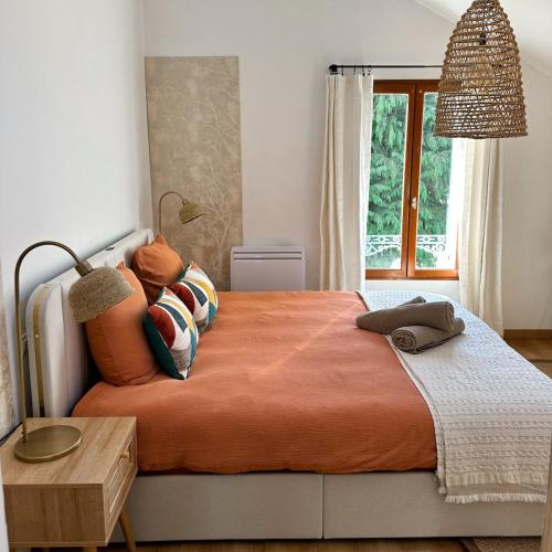 a bedroom with a large bed with an orange blanket at Echappée Bleue in Auvers-sur-Oise