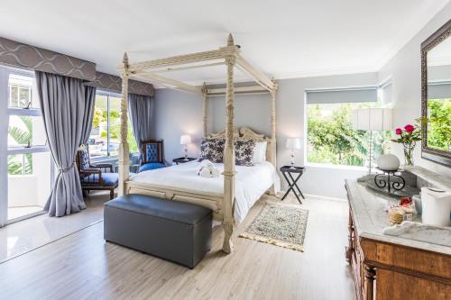 a bedroom with a canopy bed and a living room at Hermanus Manor in Hermanus