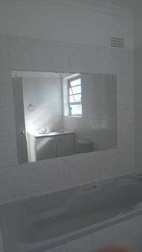 a white bathroom with a mirror and a sink at white house Bluewaterbay in Gqeberha