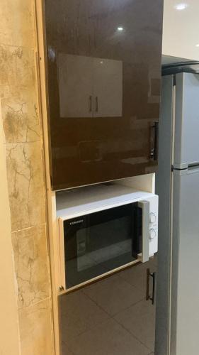 a microwave in a cabinet in a kitchen with a refrigerator at Zm apartment shehab Vib in Giza